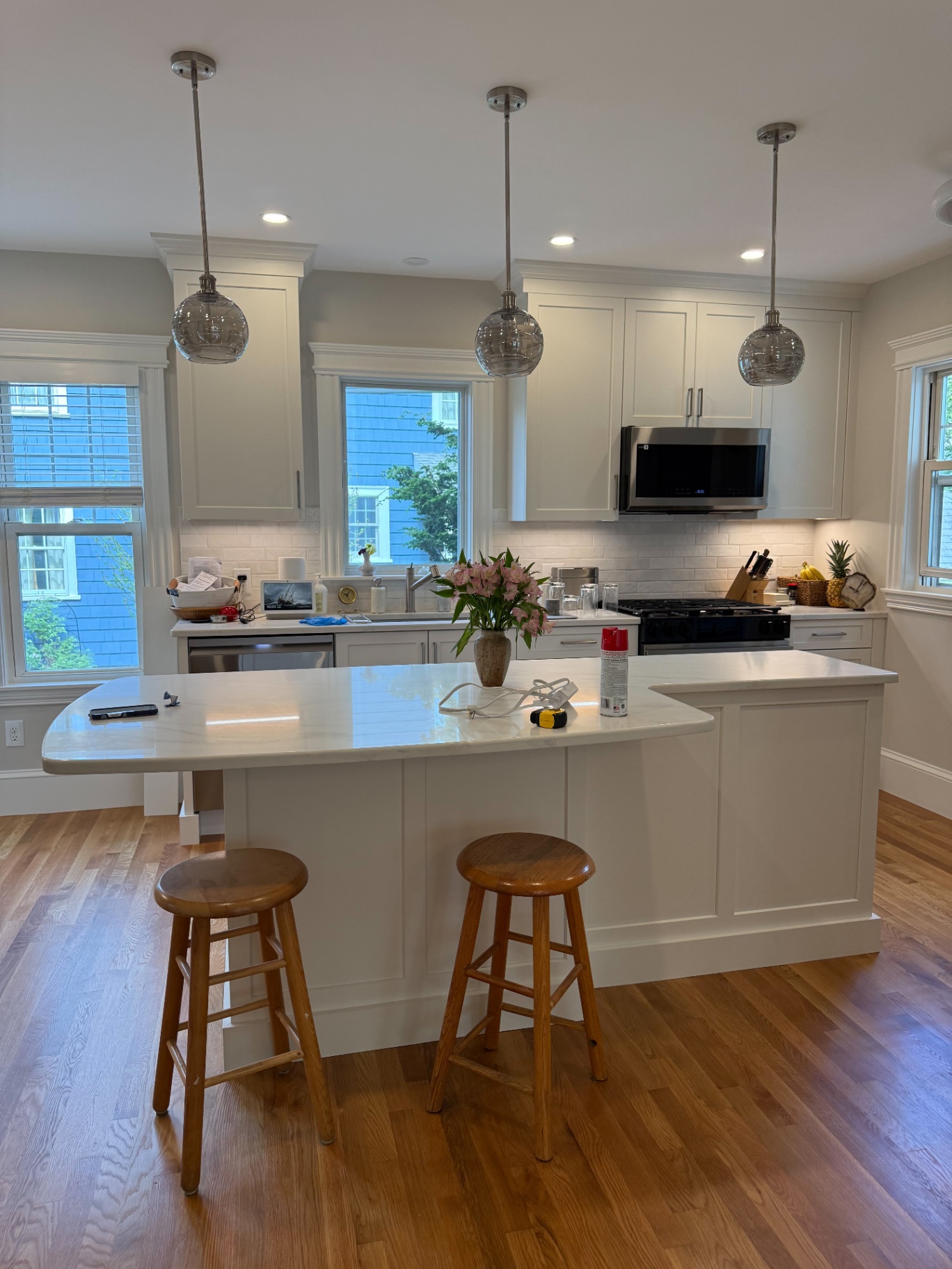 Finished kitchen remodel in Weston MA with white shaker cabinets, a marble island and glass pendant lights.